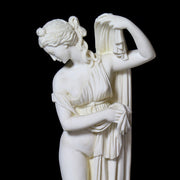 Classical Greek-style female statue in a graceful pose, featuring ornate drapery and elegant, old world European detailing. Side Angle