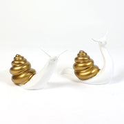 Pair of ornate snails with Baroque-inspired spiral shells and smooth, stylized bodies in a classical old world European design.