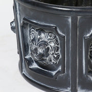 Ornate round planter with classical lion head reliefs in an old world European Baroque style, featuring detailed sculptural panels. Side Angle