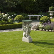 Round glass-top table with ornate, old world European base featuring a classical winged lion in a Renaissance style. Side Angle