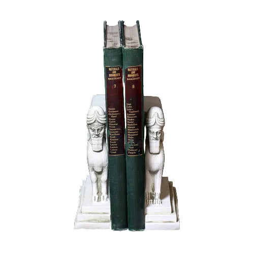 Sphinx-shaped ornate bookends with classical old world European detailing, supporting two upright hardcover books. Side View