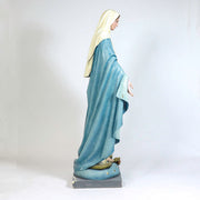 Virgin Mary statue in classical old world European style, standing with open arms on a pedestal adorned with stars and a serpent. Side Angle View