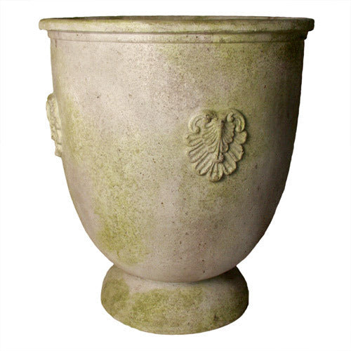 Ornate old world European urn planter with classical relief medallions and weathered, moss-accented surface.