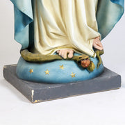 Virgin Mary statue in classical old world European style, standing with open arms on a pedestal adorned with stars and a serpent. Different Angle