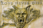 Baroque-style ornate plaque featuring a fierce, snarling gargoyle face with three wolf heads and "Love Never Dies" inscription above.