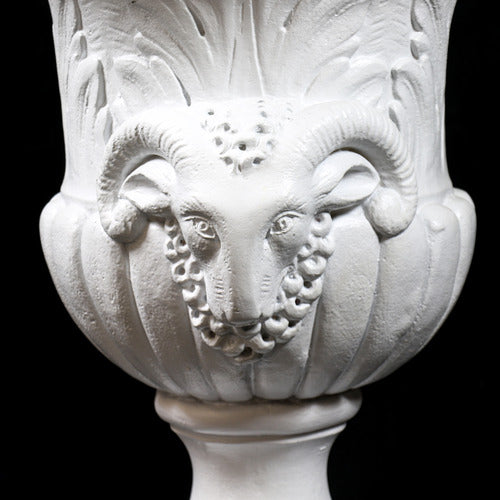 Ornate classical urn with Baroque detailing, acanthus leaf motifs, and ram head accents on a pedestal base. Side Angle