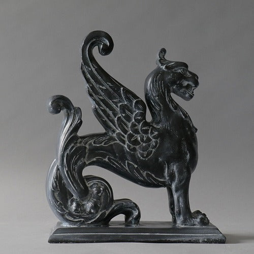 Griffin statue with ornate wings and classical detailing in an old world European, medieval style on a rectangular base. Side Angle
