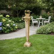 Ornate classical pedestal with decorative capital and square base, topped with a small potted plant, old world European style. Side Angle