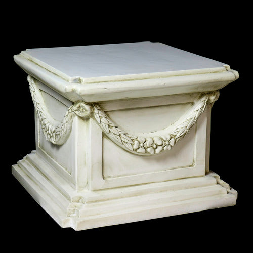 Classical pedestal with ornate garland detailing, square base, and stepped edges in an old world European architectural style. Different Angle
