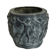 Ornate planter with classical Greek relief of dancing figures and intricate old world European detailing, leafy plant inside. Side Angle