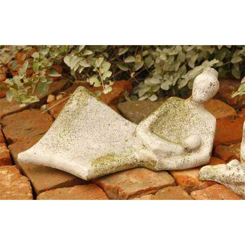 Reclining abstract figure with simplified features, evoking old world European and classical sculptural style, set on rustic bricks.