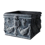 Square planter with ornate Baroque reliefs, classical shield motifs, and intricate garland detailing in old world European style. Side View
