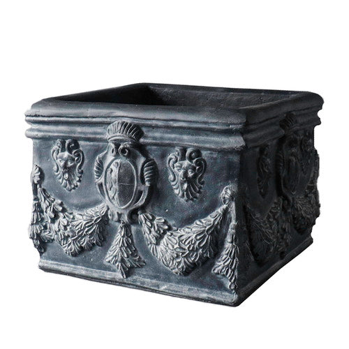 Square planter with ornate Baroque reliefs, classical shield motifs, and intricate garland detailing in old world European style. Side View