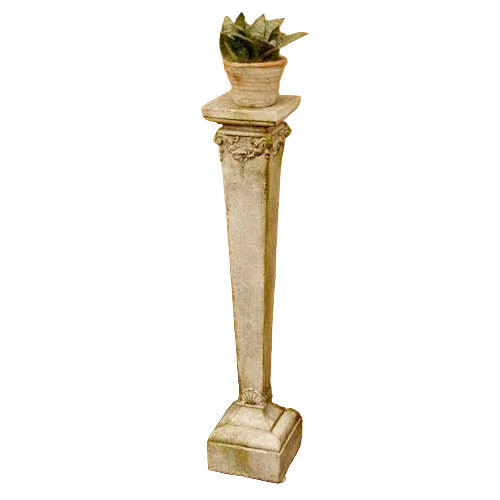 Ornate classical pedestal with decorative capital and square base, topped with a small potted plant, old world European style.
