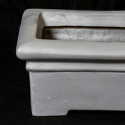 Rectangular planter with wide rim and stepped base, featuring classical old world European architectural lines and understated ornate detailing. Side Angle