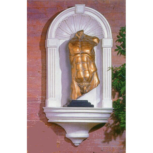 Classical Greek-style male torso sculpture displayed in an ornate arched wall niche with fluted columns and shell motif.