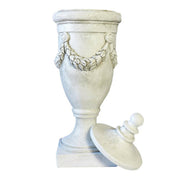 Ornate classical urn with garland relief and pedestal base, featuring a detached finial lid, in old world European style. Side View
