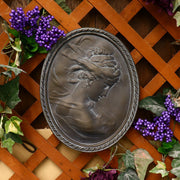 Classical oval wall plaque featuring a Baroque-style female profile with flowing hair and ornate detailing in relief. Side Angle