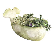 Whale-shaped planter with ornate, old world European detailing, filled with lush greenery and trailing vines.