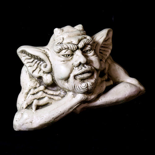 Grotesque gargoyle head with pointed ears and ornate facial features in a medieval Gothic style, resting on crossed arms. Different Angle
