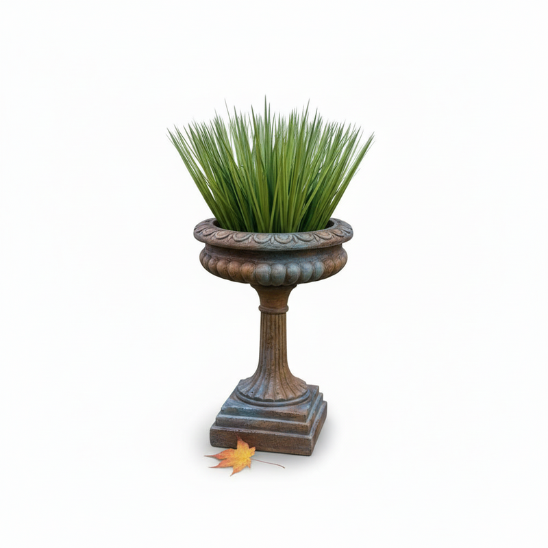Ornate classical urn planter with fluted pedestal base and scalloped rim, featuring lush grass, old world European style
