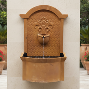 Wall fountain with ornate old world European design, arched top, classical floral motif, and woven basket detail. Side Angle