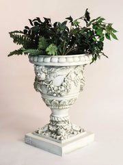 Ornate Baroque urn planter with cherub reliefs, classical garlands, and intricate old world European detailing on a square pedestal base Side Angle