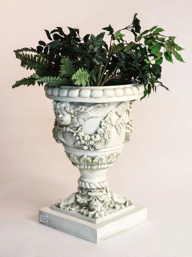 Ornate Baroque urn planter with cherub reliefs, classical garlands, and intricate old world European detailing on a square pedestal base Side Angle