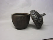 Acorn-shaped container with ornate, old world European style lid featuring detailed leaf and textured pattern Side Angle
