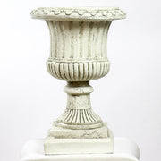 Ornate classical urn planter with fluted detailing atop a Greek-inspired Ionic column pedestal, featuring old world European style. Side Angle