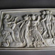 Classical Greek-style relief plaque featuring dancing figures and musicians in an ornate, old world European composition. Side Angle