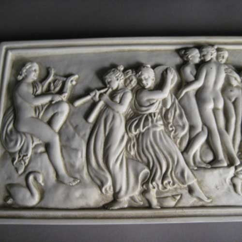 Classical Greek-style relief plaque featuring dancing figures and musicians in an ornate, old world European composition. Side Angle