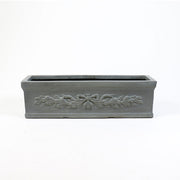 Rectangular planter box with ornate classical relief featuring a bow and garland motif in an old world European style. Side Angle
