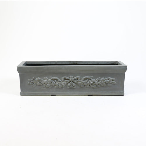 Rectangular planter box with ornate classical relief featuring a bow and garland motif in an old world European style. Side Angle