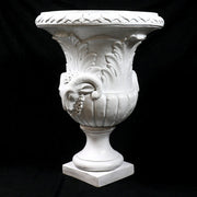 Ornate classical urn with Baroque detailing, acanthus leaf motifs, and ram head accents on a pedestal base. Different Angle
